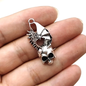 Gothic silver skull pendant with bat wings held in hand for jewelry making DIY