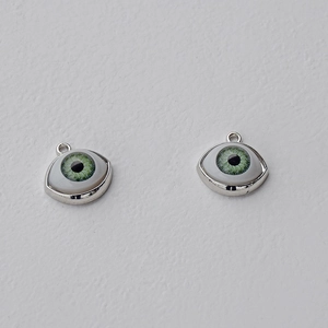 Macro detail of green evil eye pendants with silver metal edges for DIY jewelry making