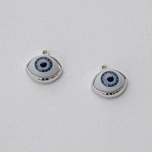 Macro shot of silver-framed blue evil eye charms with detailed iris and metal hanging loops