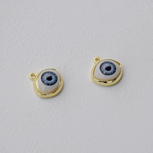 Close-up of golden evil eye pendants with blue and white details for jewelry making