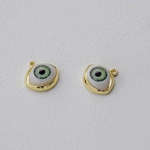 Macro detail of alloy evil eye charms with green pupils and polished gold plating