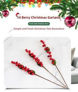 Detailed view of three artificial red berry stems with green leaves on marble surface