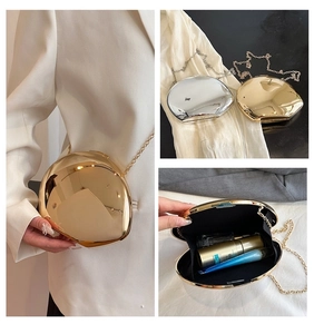 Detailed interior of shell-shaped metal clutch bag with black lining and gold chain strap