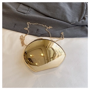 Chic gold mirrored acrylic clutch bag with metal chain strap on a blazer background
