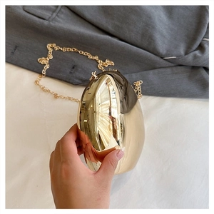 Close-up of golden egg-shaped acrylic evening clutch bag with mirrored metallic finish