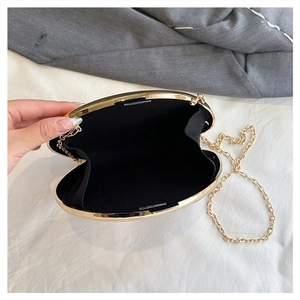 Detail of black acrylic box clutch with gold metal frame and interior storage
