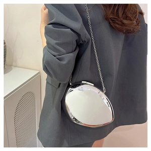 Silver metallic irregular box bag with chain strap worn over a grey blazer