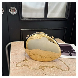 Elegant gold egg-shaped acrylic clutch with metallic chain strap on a stone texture surface