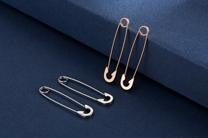 Close-up of safety pin earrings in rose gold and silver finishes with polished texture