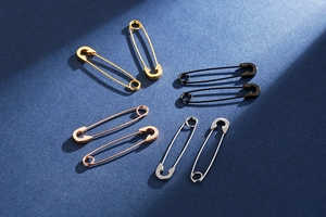 Macro view of safety pin earrings in gold, silver, rose gold, and gunmetal finishes