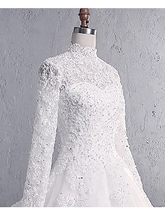 Close-up of high neck lace bridal gown featuring intricate floral embroidery and sequins