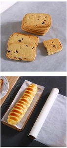 Detail of golden cranberry cookies and striped bread on non-stick baking paper sheets