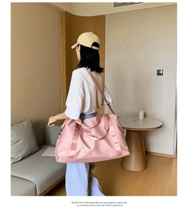 Pink waterproof fitness bag shown on model featuring large capacity and shoulder strap