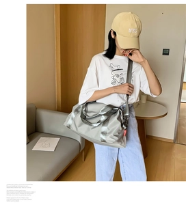 Silver-grey waterproof nylon travel bag shown in hand and on shoulder for gym or travel