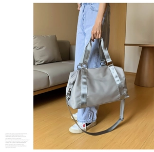 Detail of grey waterproof fitness travel bag with woven handle on wooden floor