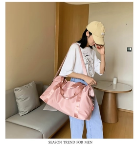 Pink waterproof travel bag with adjustable strap worn by a model in a home setting