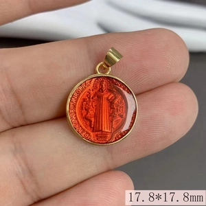 Close-up of a 17.8mm gold round Saint Benedict pendant with red enamel inlay details