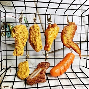 Detailed close-up of realistic food keychains including fried chicken and steak on a grid