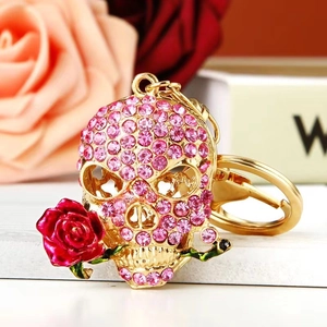 Macro view of gold skull keychain with pink rhinestones and a red enamel rose detail