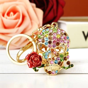 Macro shot of skull keychain encrusted with colorful rhinestones holding a red rose