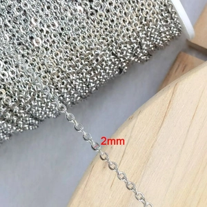 Macro detail of 2mm silver stainless steel cross chain on a rustic wooden background