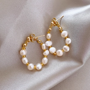 Elegant gold hoop earrings featuring irregular freshwater pearls on soft grey silk fabric