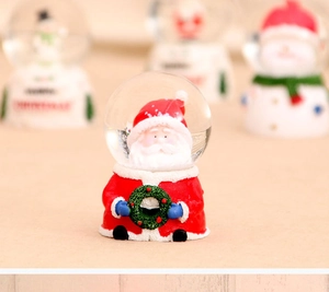 Close-up of glowing Santa Claus crystal ball with resin base and snow particles