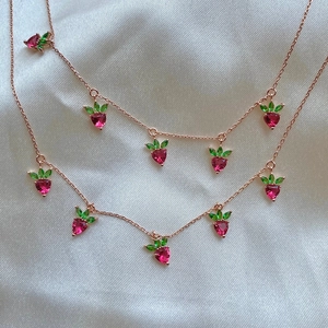 Double-layered rose gold strawberry necklace with red heart-shaped crystals on silk