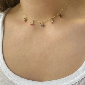 Detail of woman wearing a gold chain necklace with colorful crystal fruit pendants
