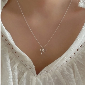 Elegant 925 sterling silver bow necklace shown on a model neck with a lace background