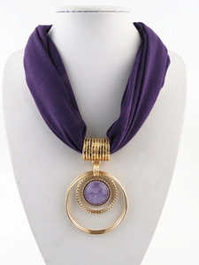 Dettaglio della collana a sciarpa viola con ciondolo ad anello dorato e gemma viola