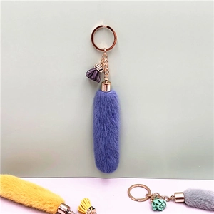 Detailed view of plush keychains with tassels in purple, yellow, and grey colors