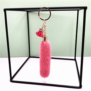 Detail of pink faux fur keychain with gold chain and small tassel on a metal stand