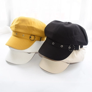 Classic newsboy octagonal caps in black, beige, white, and yellow with metal rings