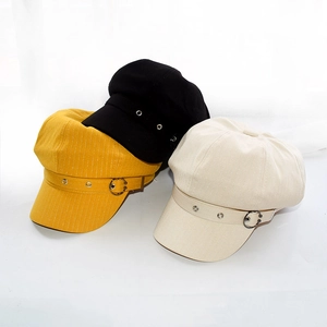 Detailed view of newsboy caps in yellow, black, and beige with metallic buckles
