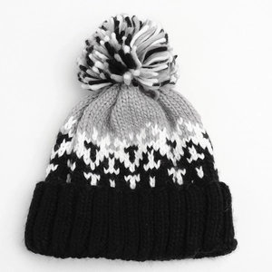 Detail of the knit winter hat featuring a multi-color pompom and geometric diamond pattern