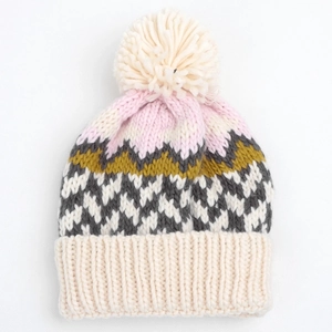 Detail of multi-color geometric knit beanie featuring a fuzzy pom-pom and thick ribbed cuff