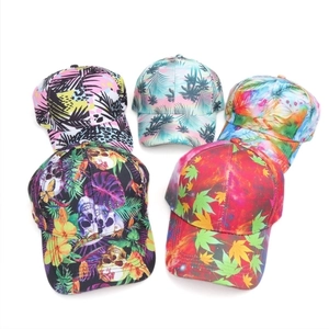 Five assorted baseball caps with tropical leaf and skull prints on a white background