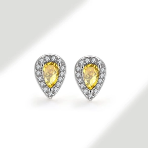 Macro shot of silver stud earring featuring pear-cut yellow gemstone and zircon halo