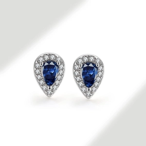Macro shot of silver teardrop stud earrings with blue sapphire zircon and white halo stones