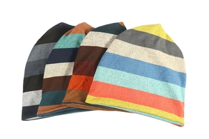 Detail shot of four striped knit beanies in various colors stacked on white background