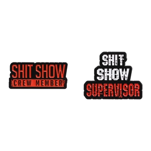 Red and white enamel pin set featuring humorous Shit Show Crew Member and Supervisor text