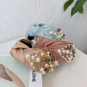 Detail of knotted headbands in silk texture with white pearls and gold metal beads