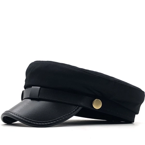 Detail of black military cap featuring matte fabric and a glossy faux leather brim