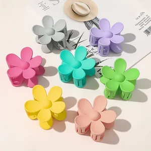 Close-up of matte flower hair claws in seven pastel macaron colors on a magazine background