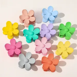 Flat lay of 11 colorful matte flower hair claws in sweet pastel macaron tones