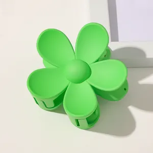 Close-up of a large matte green flower hair claw clip on a neutral background