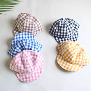 Flat lay detail of plaid cotton baby baseball caps in brown, blue, pink, and orange