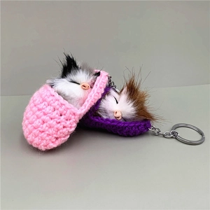 Detail of cute sleeping cat plush keychains in pink and purple knitted baskets