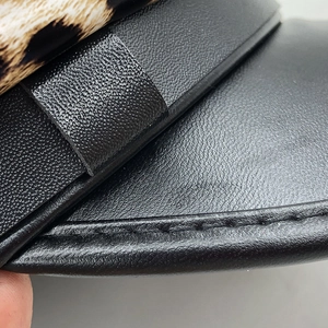 Detail of leopard print fabric stitched onto black textured leather military style cap